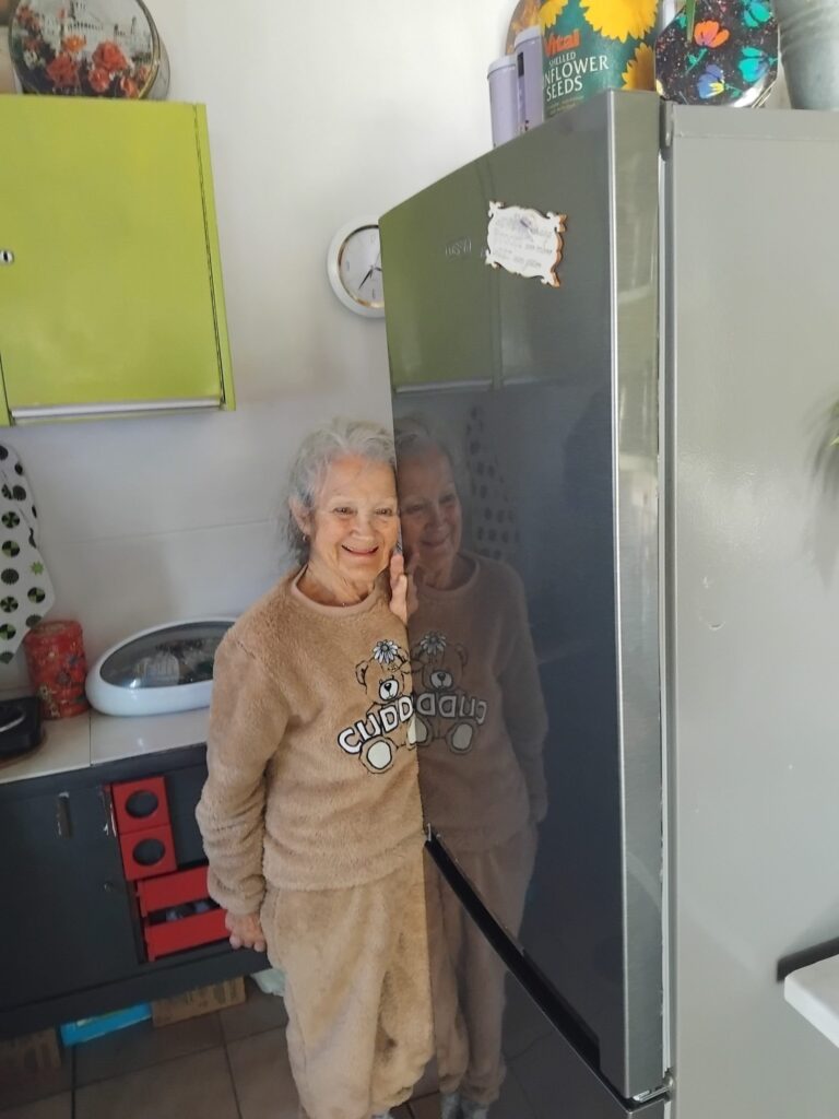 Happy client with her repaired fridge in her kitchen — Welkom Appliance Repairs